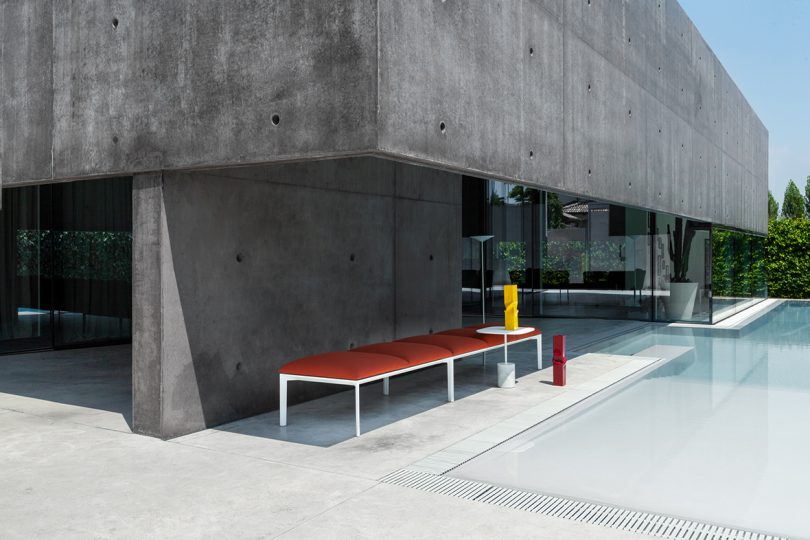 red outdoor bench under a concrete overhang
