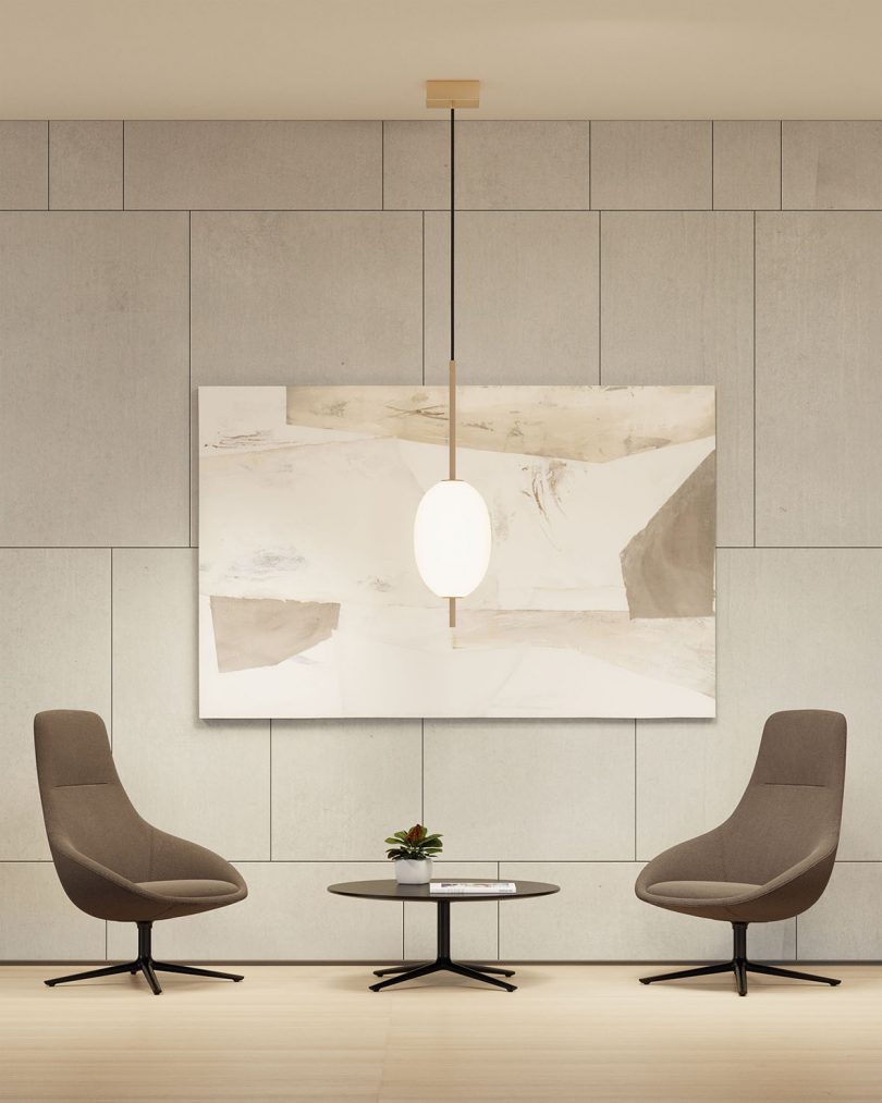 two greige lounge chairs with coffee table and pendant lamp in front of a cream colored wall