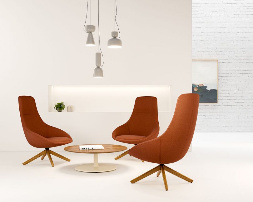 three red lounge chairs with coffee table and pendant lighting in front of a white wall