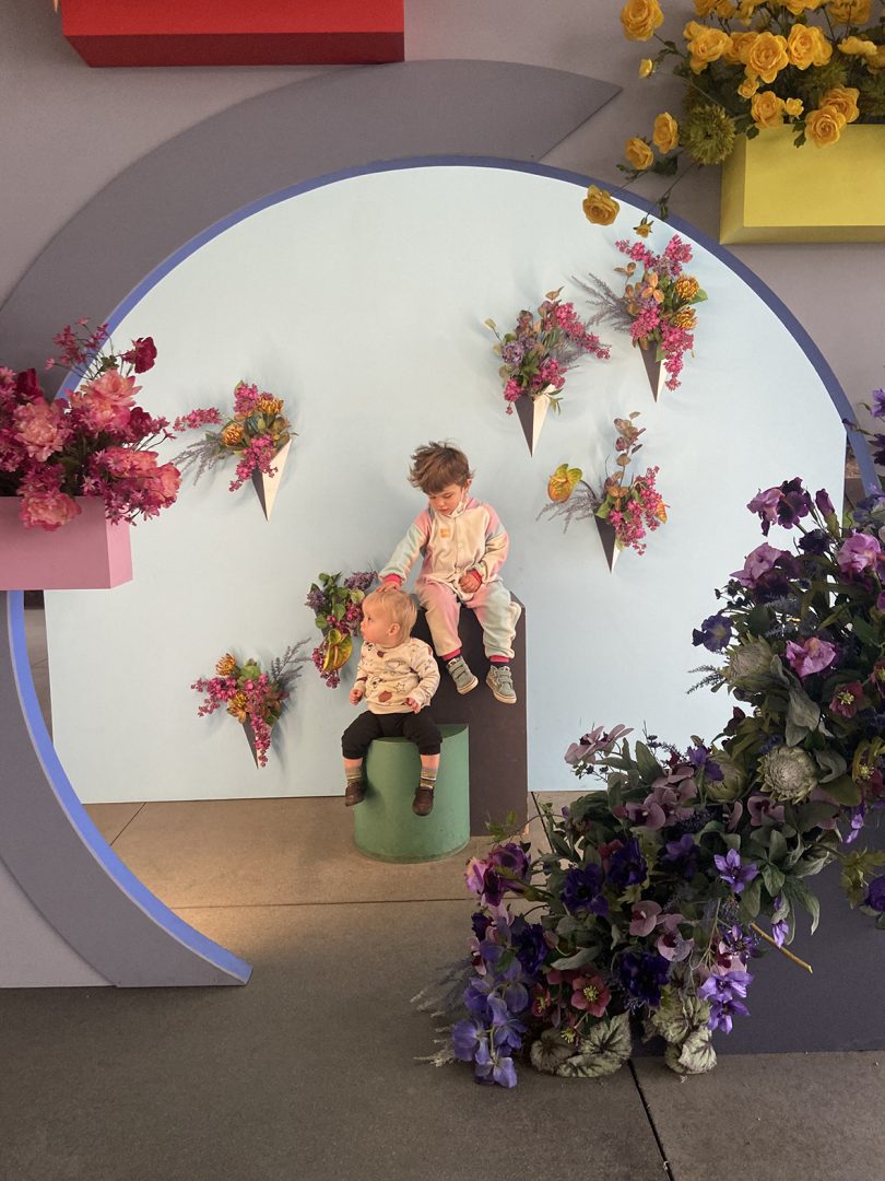 two young light-skinned children seen through a cutout circle surrounded by florals