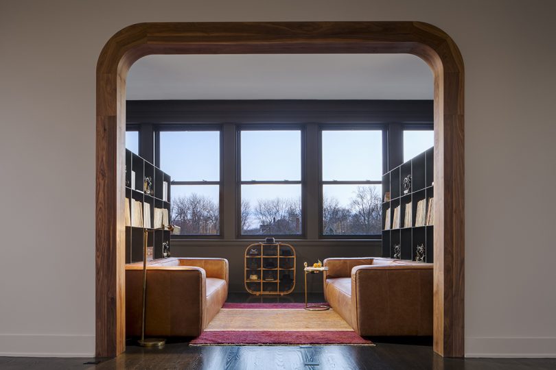looking through a doorway into a lounge with two large leather sofas and a wall of windows