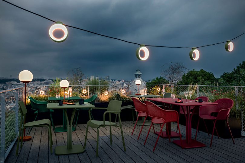 rooftop deck at night with dining tables and chairs and string lights