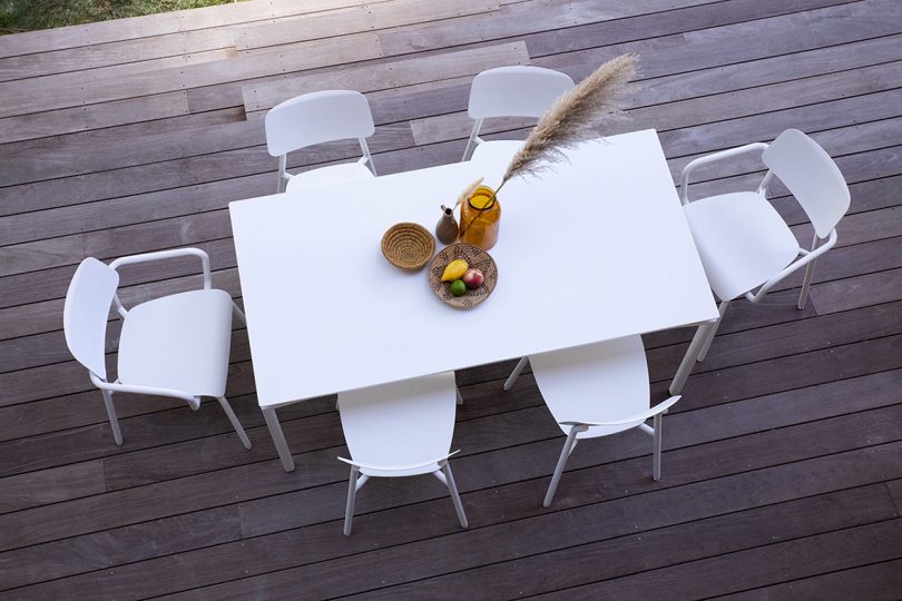 overhead photo of white outdoor dining table and chairs on deck