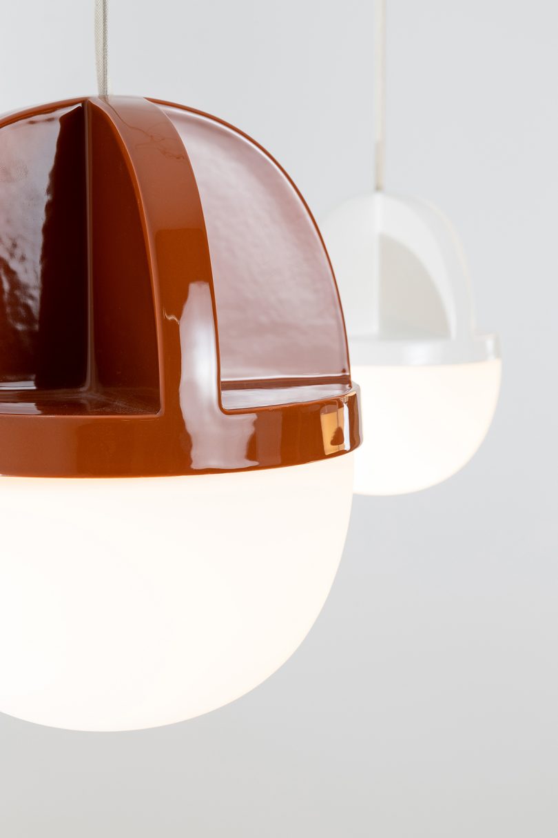 detail of white and rust colored pendant lights hanging from the ceiling in a white space