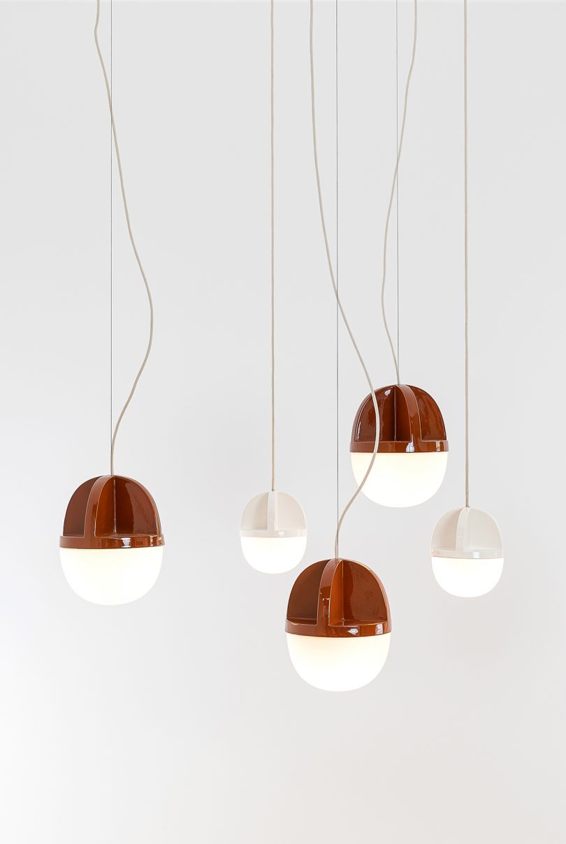 white and rust colored pendant light hanging from the ceiling in a white space