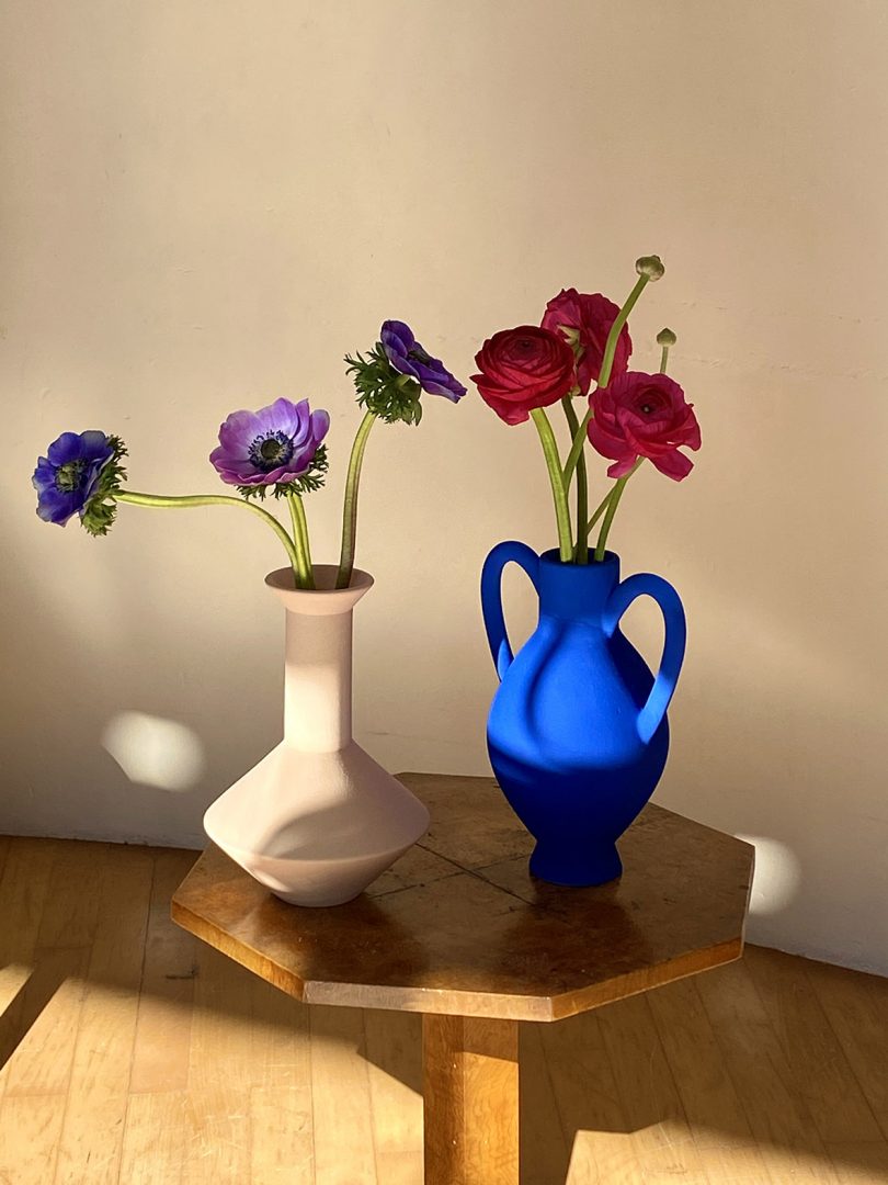 two vases with flowers sitting on wood side table