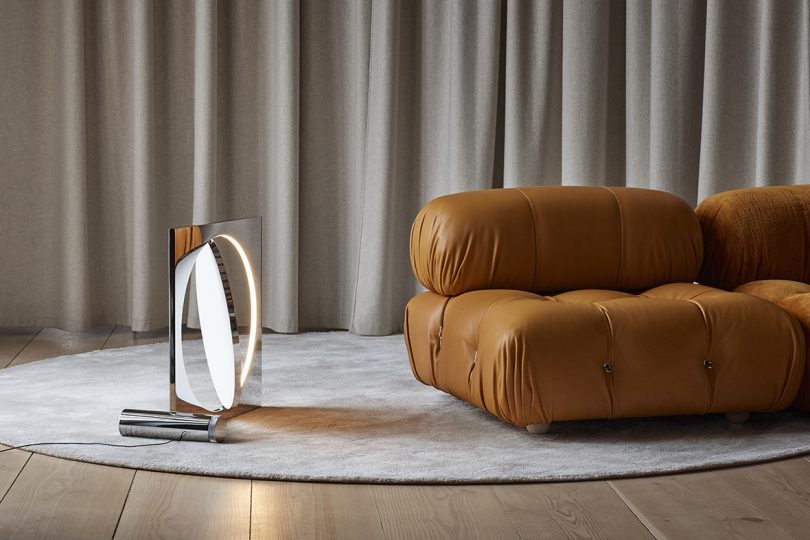 modern metal floor lamp on floor next to brown leather sofa