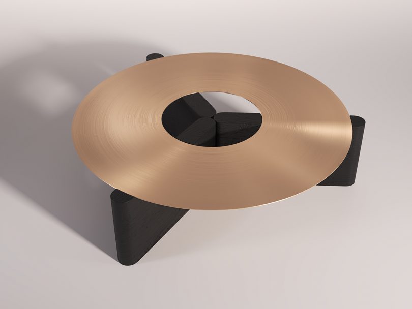 round gold coffee table with black three leg base