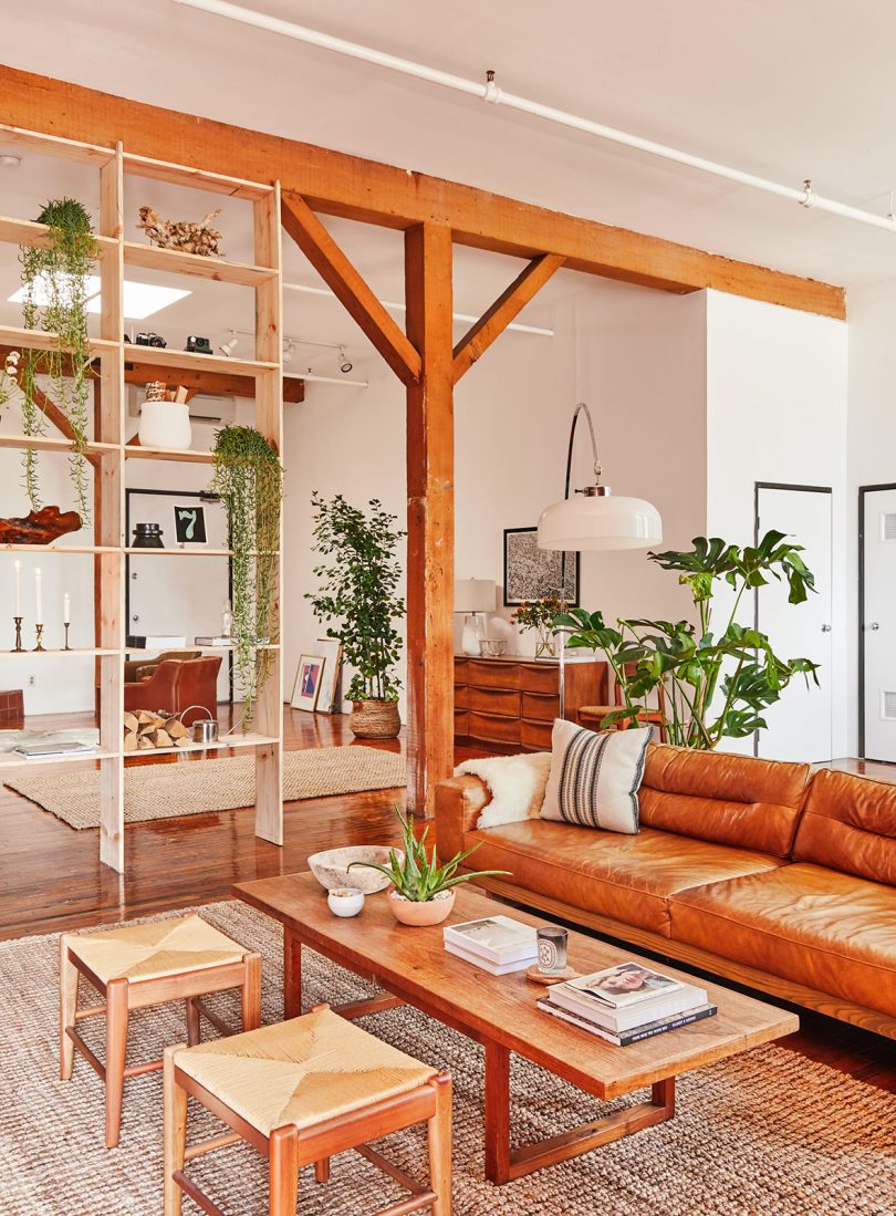 loft with wooden beams and shelves and tan leather and wood furniture