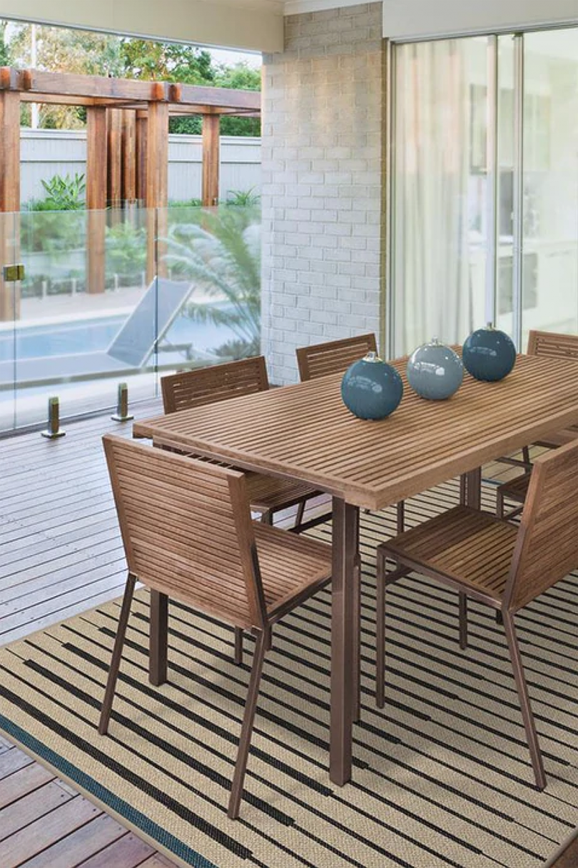 mesa y sillas al aire libre sobre una alfombra de yute y rayas negras