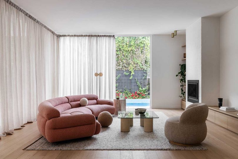 minimal white living rom with modern decor including a pink curved sofa and rounded armchair