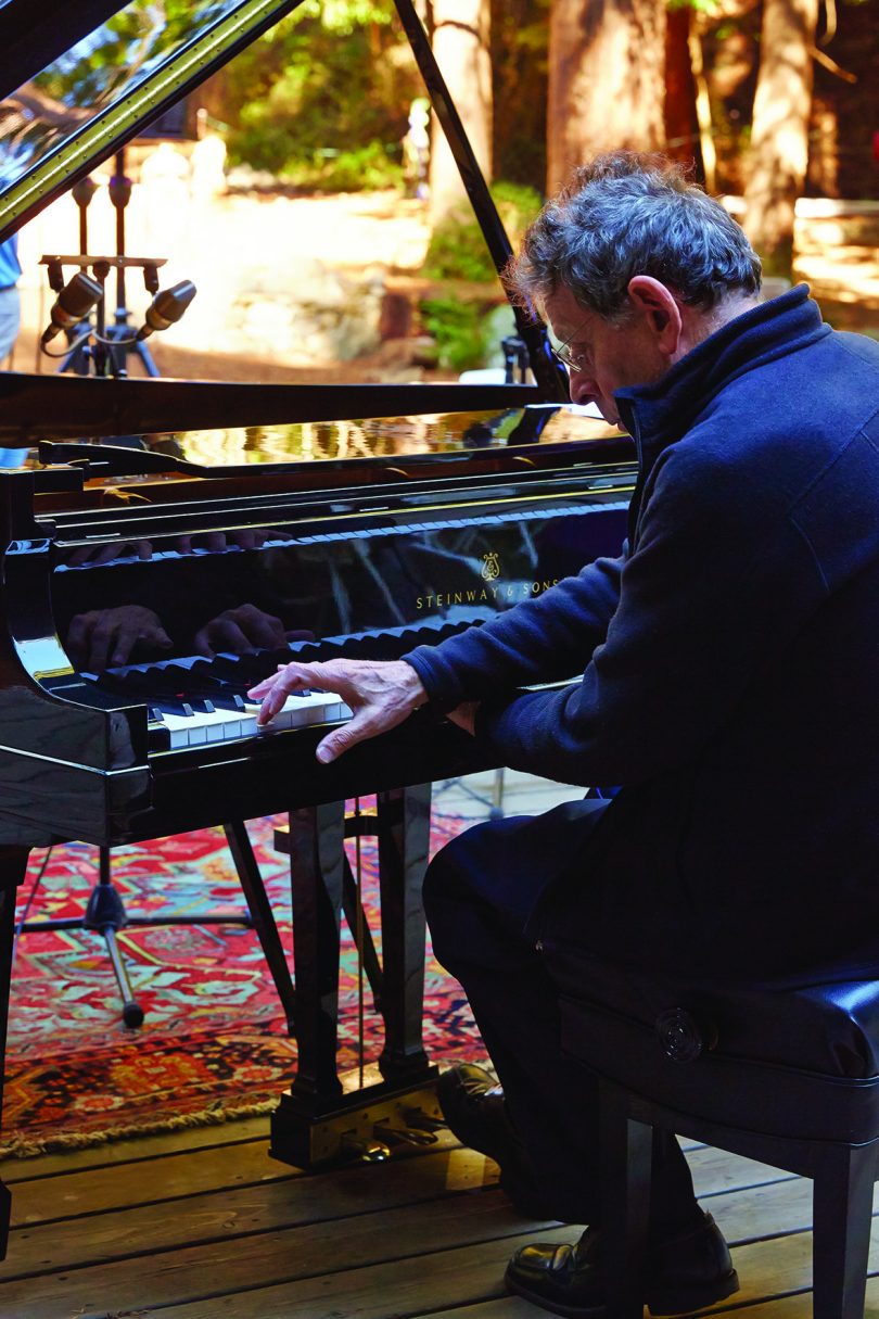 light-skinned older man with greying hair playing a black piano
