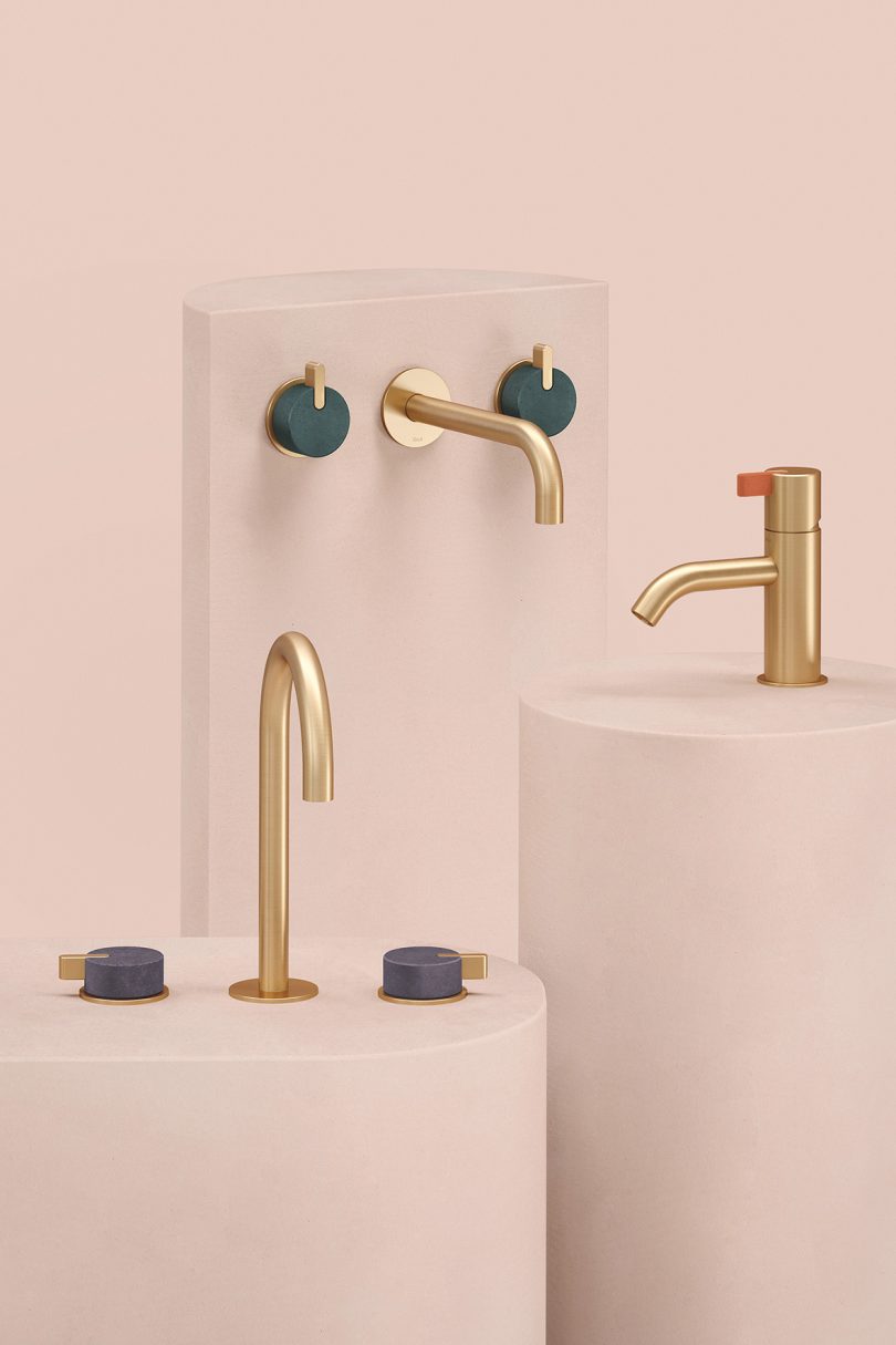 three brass faucets on light pink background