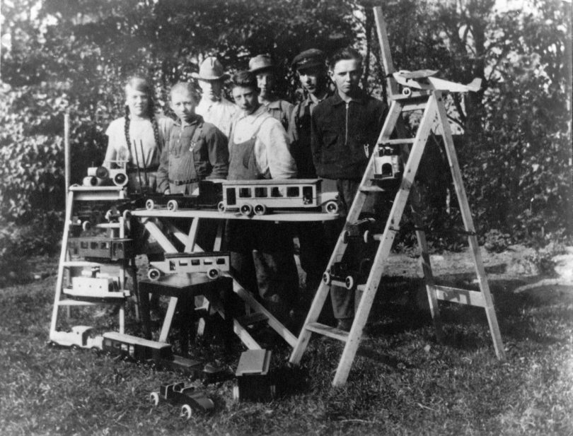 old black and white photo of men surrounded by wooden toys on tables