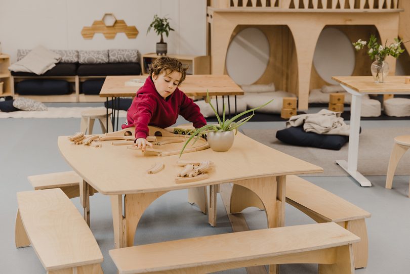 light-skinned boy sitting at a wooden table with benches and playing