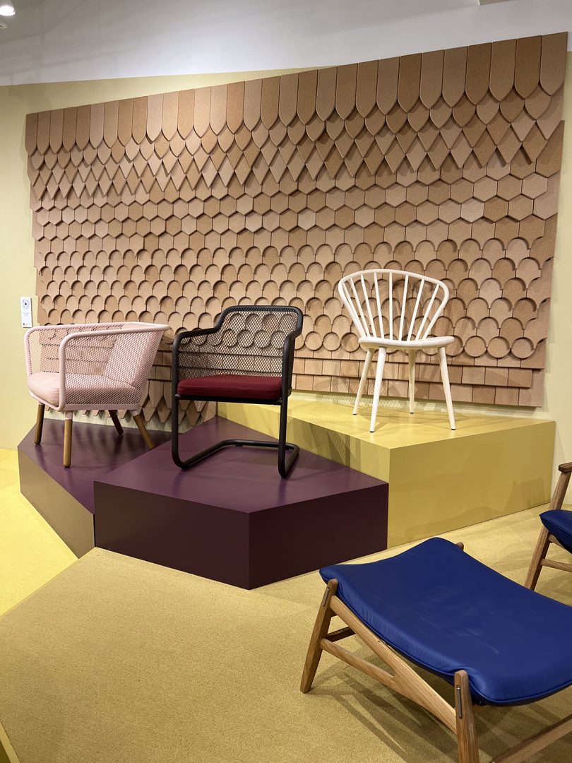 three armchairs on yellow and maroon pedestals in front of wood acoustic wall