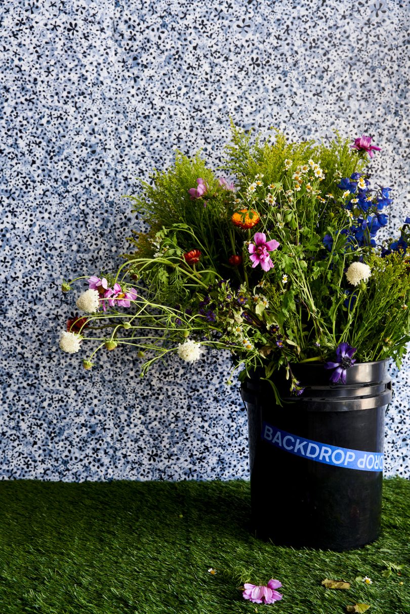 black, white, and blue flower wallpaper with bucket of flowers in front