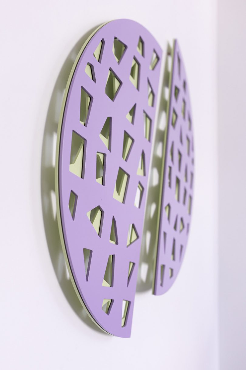 two lilac half circles with intricate woodwork pattern hanging on a wall