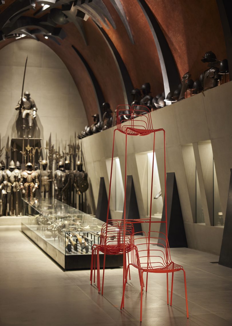 stacked modern vermillion wire chairs and stools in traditional gallery space