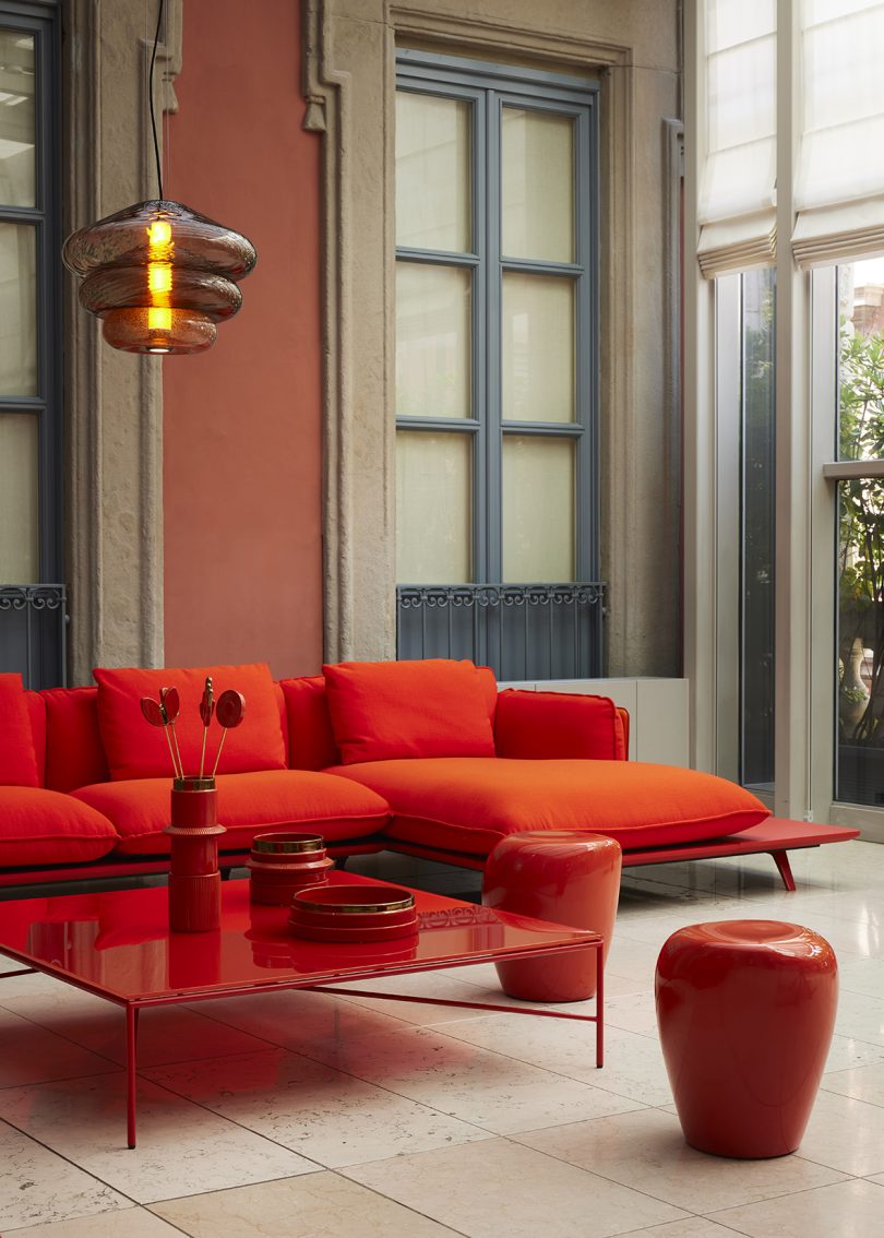 vermillion sofa, coffee table, stools, and accessories in a styled interior space
