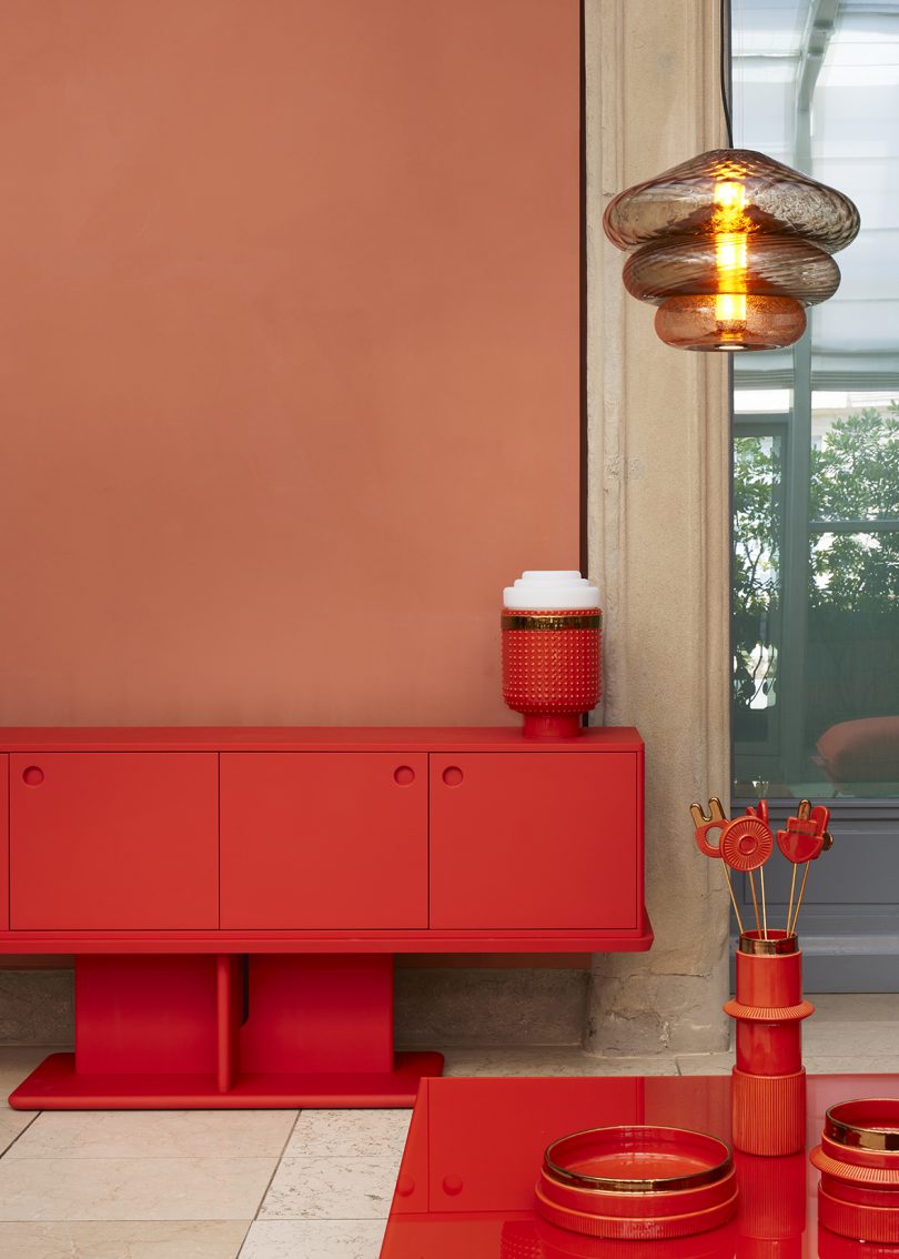 vermillion credenza, table lamp, table, and accessories in a styled interior space