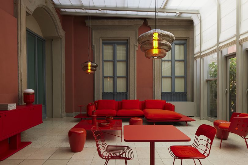 vermillion sofa, coffee table, stools, cafe table, and dining chairs in a styled interior space