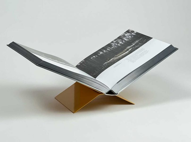 side view of a yellow metal bookstand holding a large coffee table book open