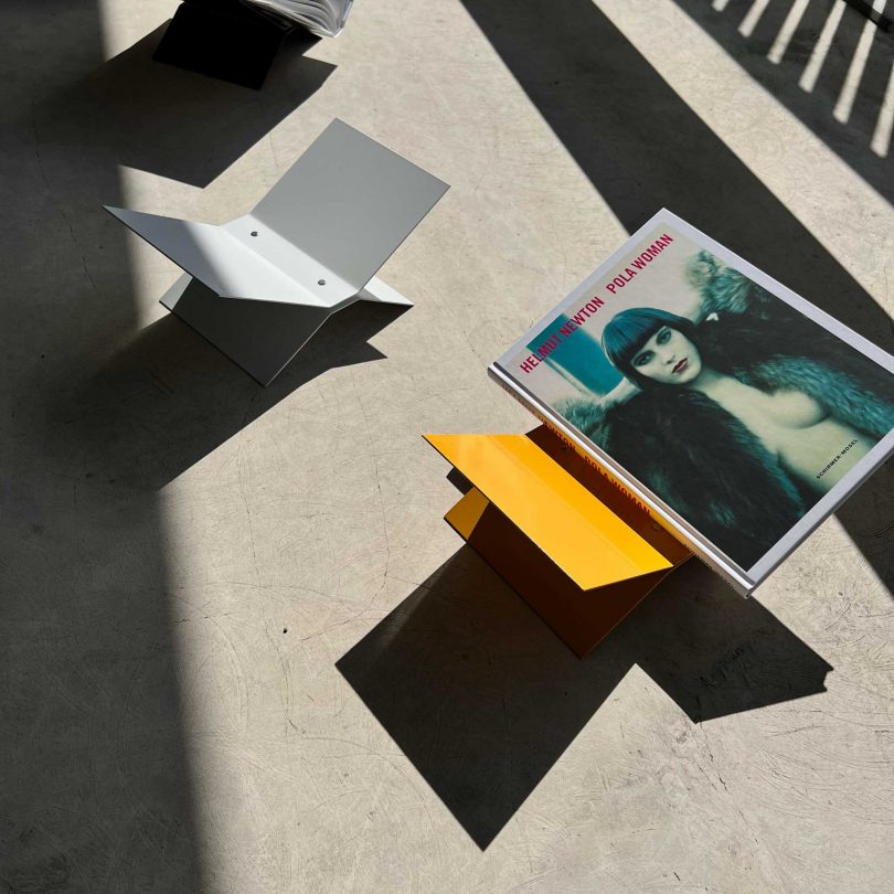 view looking down at two metal bookstands on concrete with a large book on yellow stand