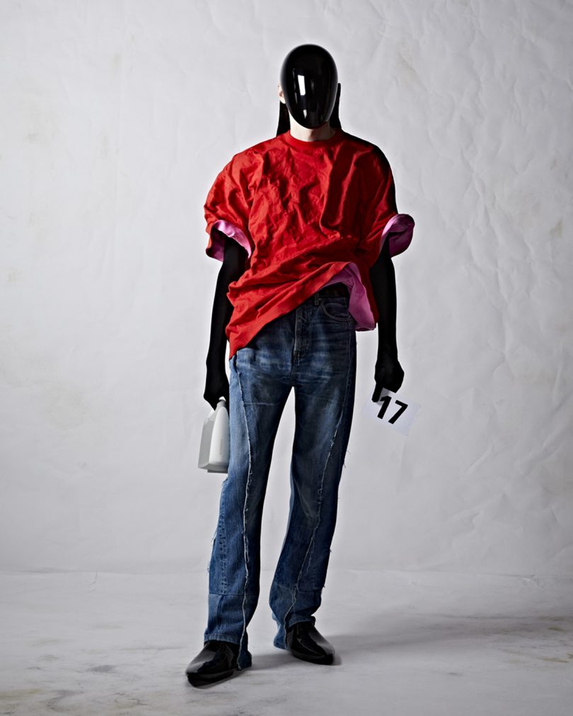 Balenciaga couture model in red top and jeans holding white Bang & Olufsen Speaker Bag.