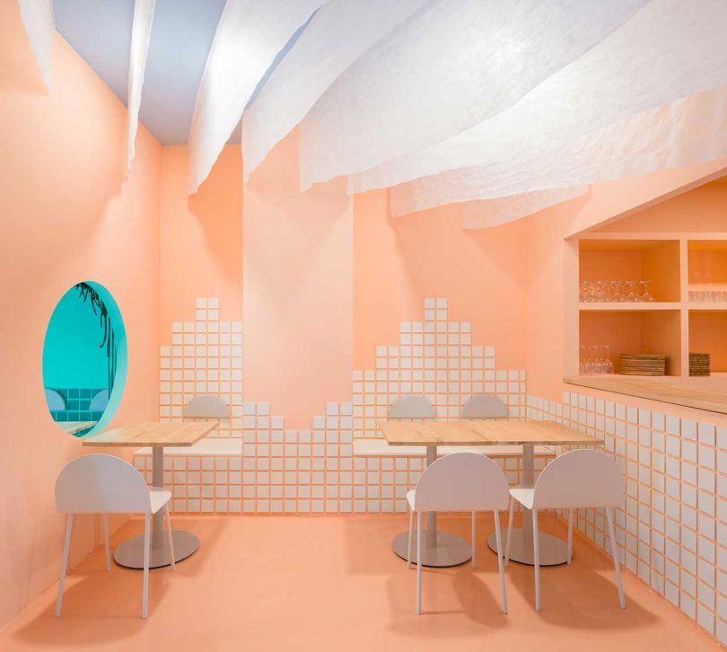 restaurant interior in peach and white color scheme with floating panels from ceiling