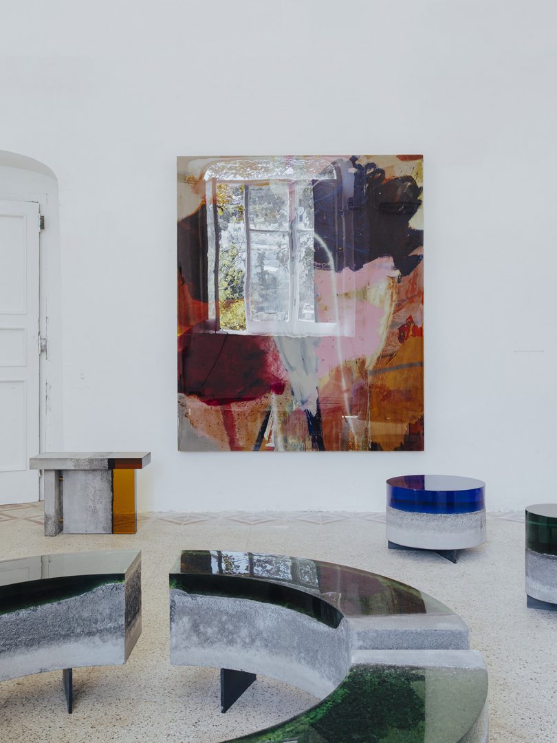 three concrete and resin tables, a coffee table, and large piece of wall art in an interior space