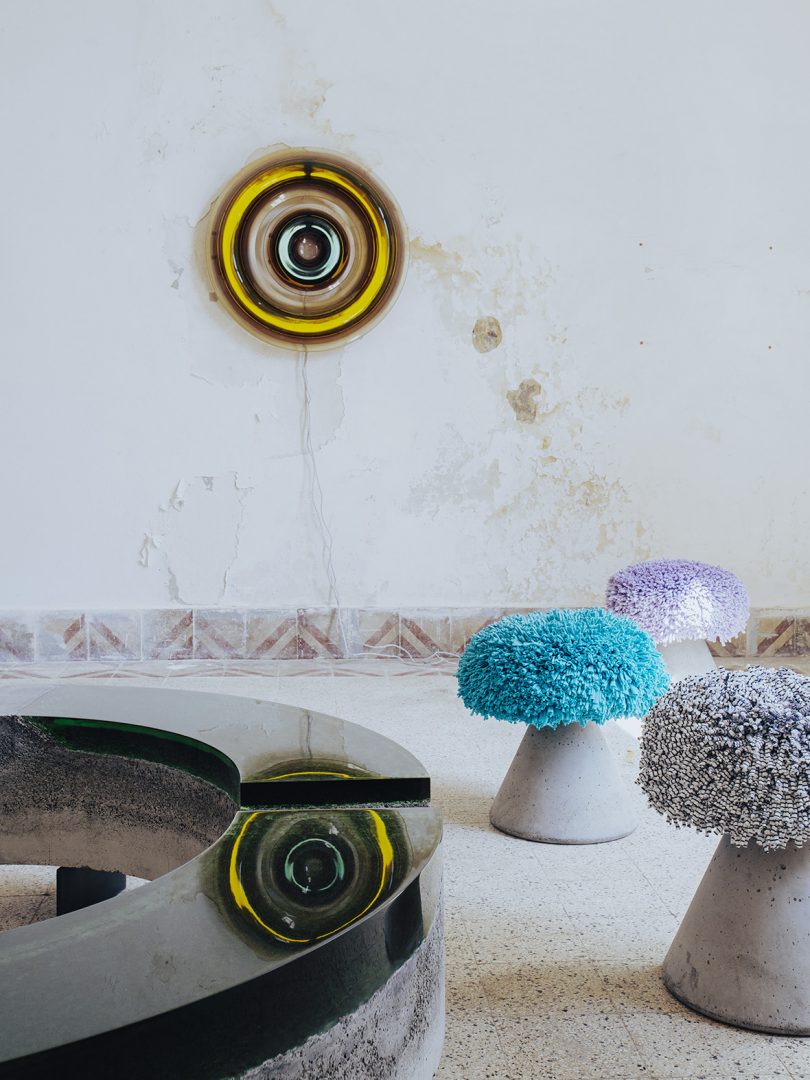 concrete and resin wall lamp, coffee table, and three stools in an interior space
