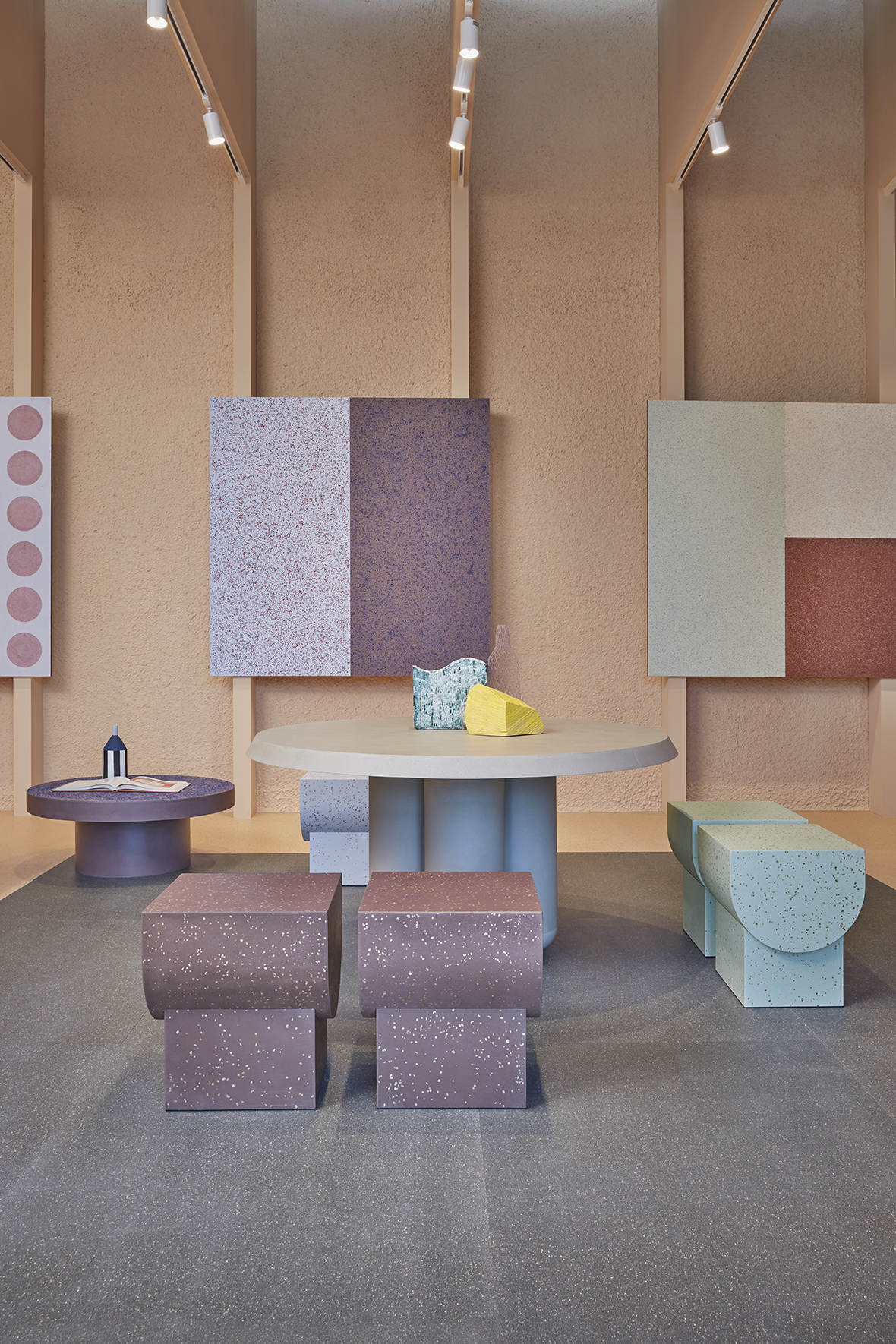 showroom featuring pastel, geometric tables, stools, and paintings