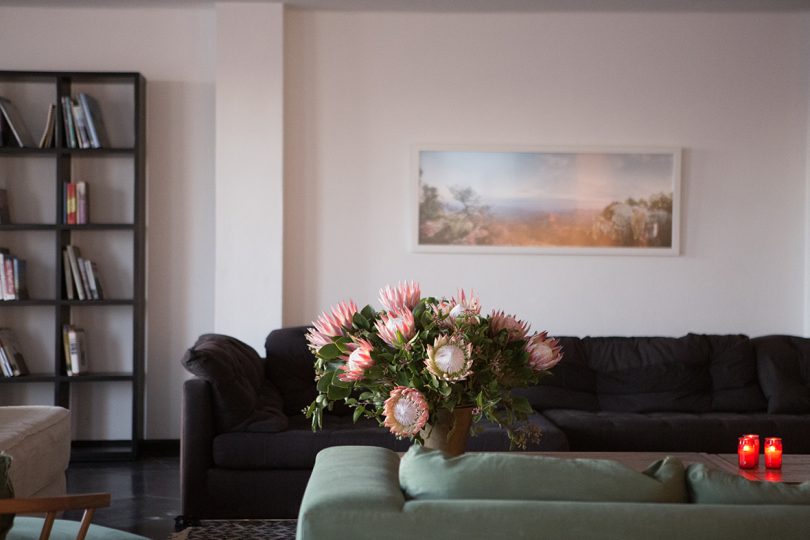 vase of flowers, two sofas, and art hanging against a white wall