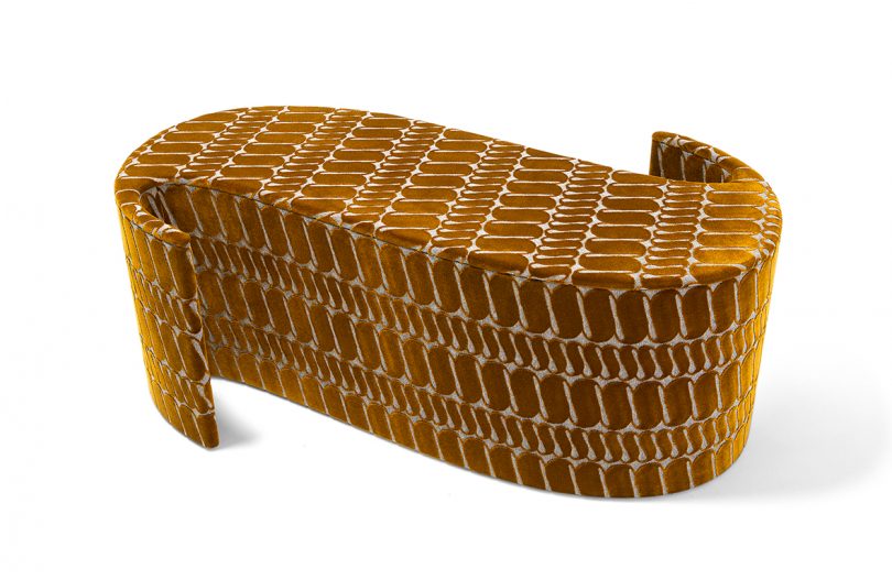 piece of furniture shaped like a tilde and covered in matching patterned fabric