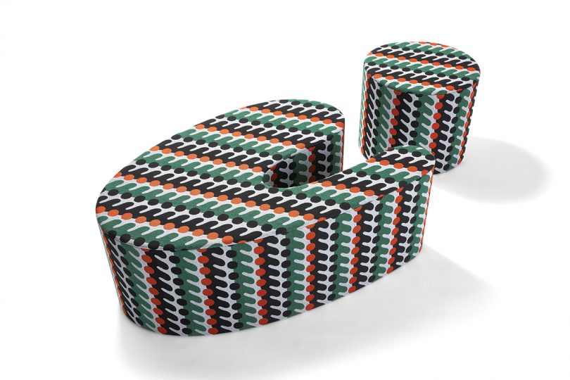 piece of furniture shaped like a lowercase i and covered in matching patterned fabric on white background