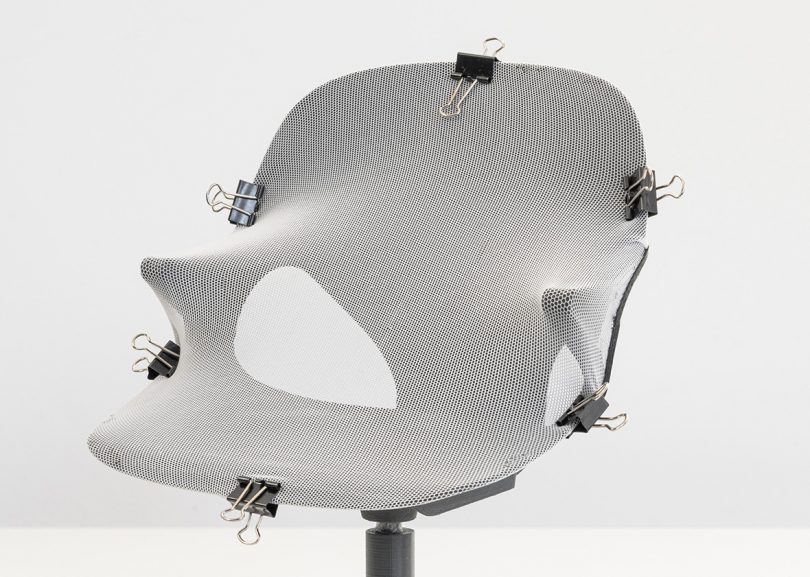 Zeph 3d-printed scale chair model with upholstery sample in white-gray attached attached using file clips around the edges.