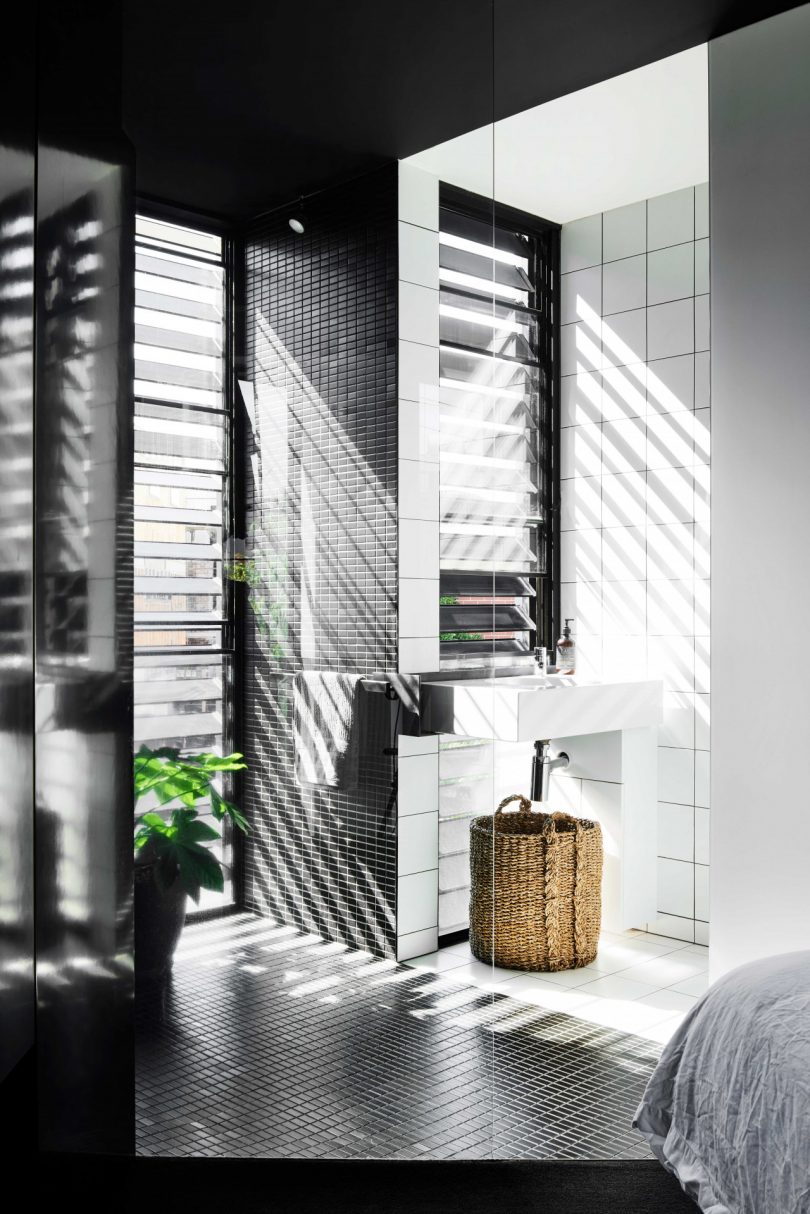 the interior of the modern house overlooking the black and white bathroom with partially open shutters