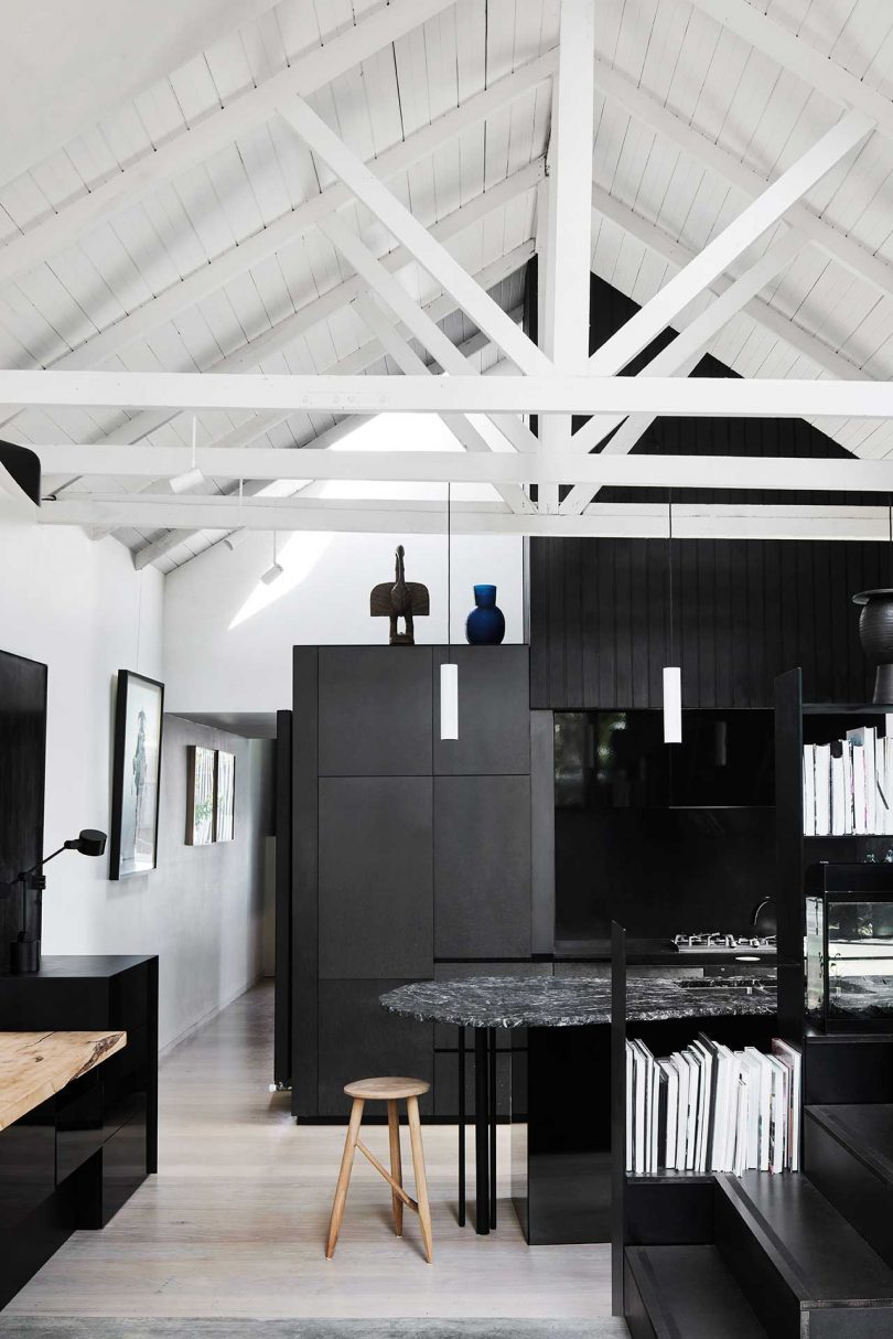 view of interior of modern home's black and white kitchen with pitched white rafters
