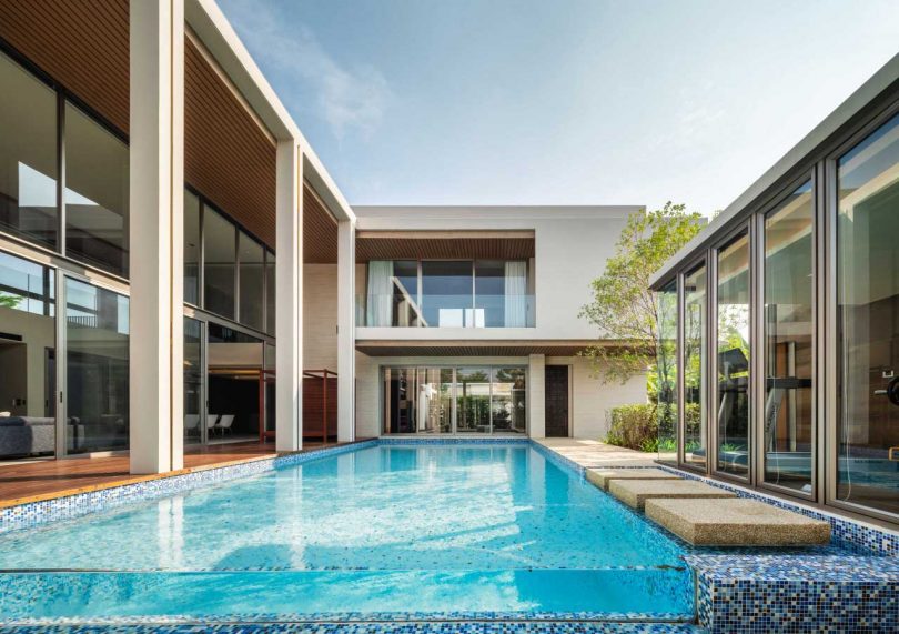 exterior view of courtyard of modern beige home with glass fronted pool