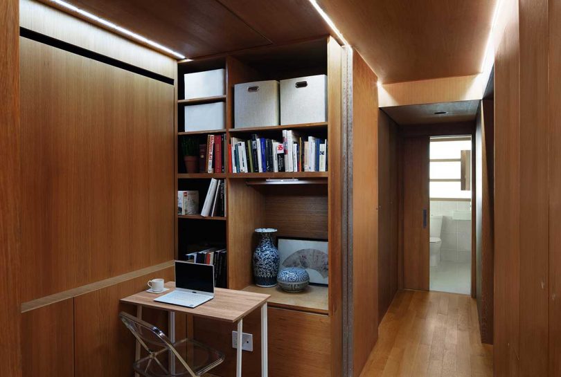 interior view of wooden hallway with sliding doors open and small desk folded down in front of shelves