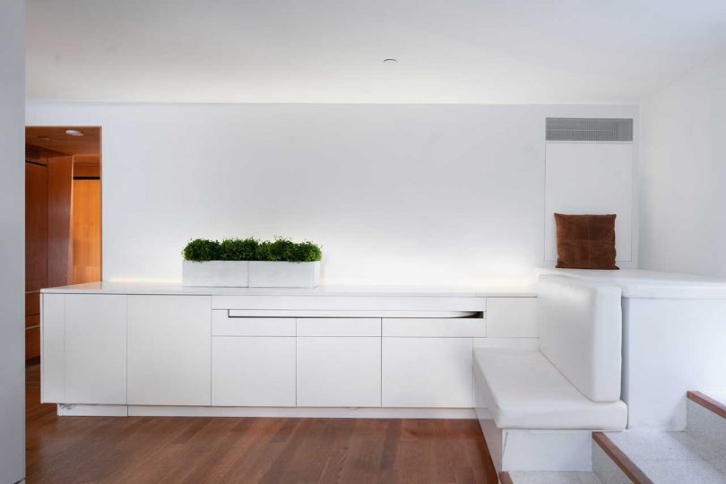 نمای داخلی آپارتمان کوچک با دیوارها و کابینت های سفید و کف چوبی