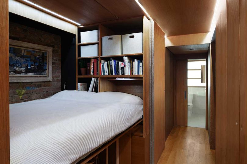 interior view of wooden hallway with sliding doors open and bed folded out by shelves