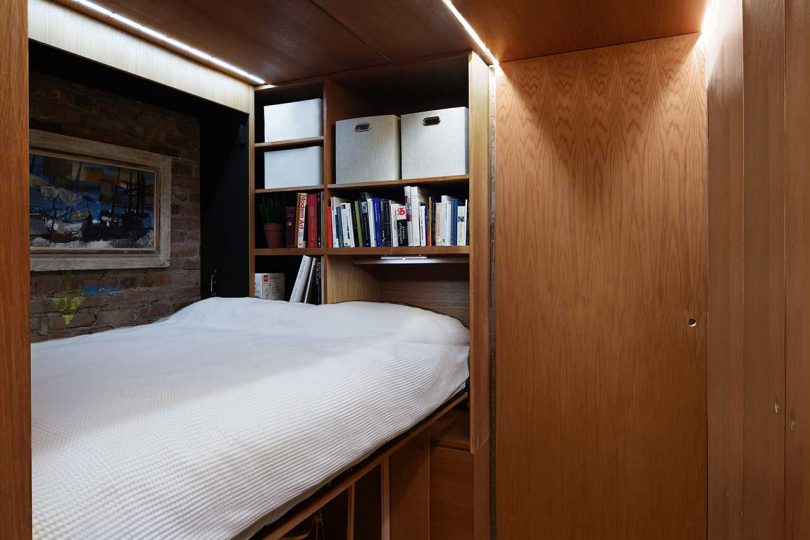 interior view of wooden hallway with sliding doors open and bed folded out by shelves
