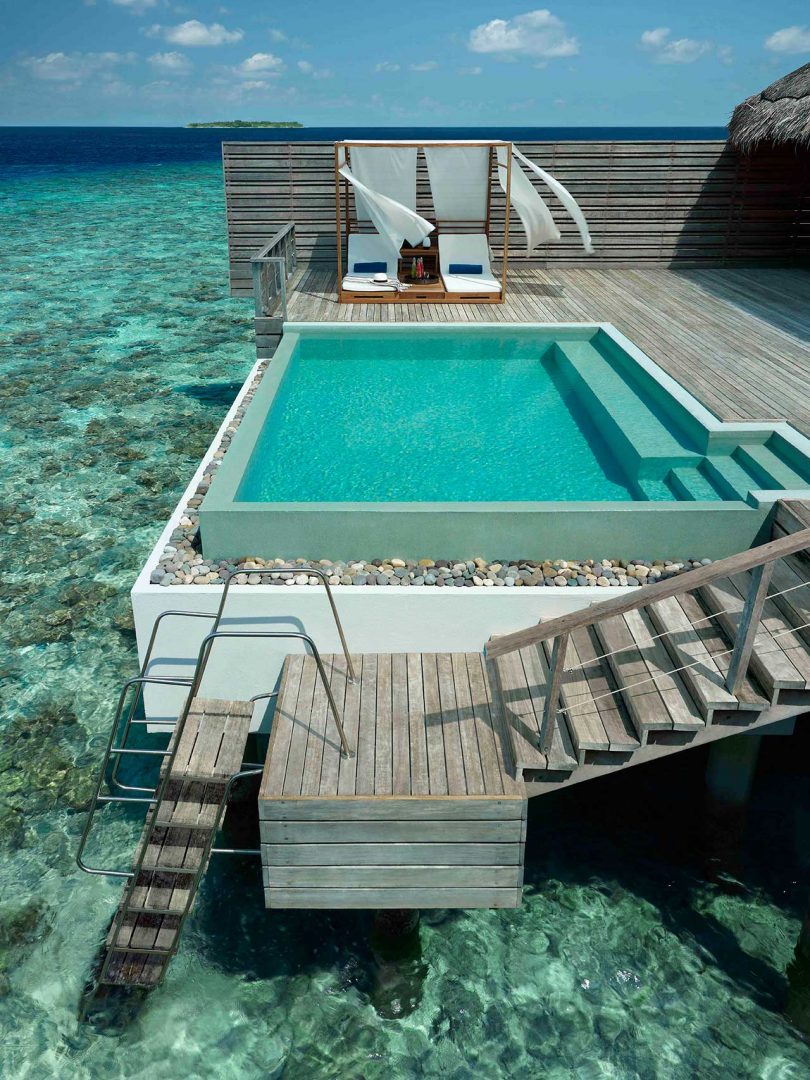looking down at an elevated swimming pool on a modern deck built over the ocean