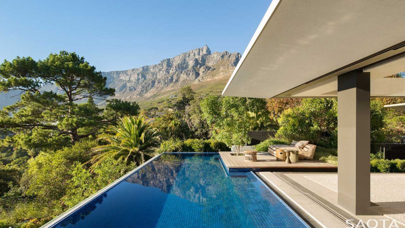 exterior of modern house in Cape Town looking at dark blue swimming pool looking out to greenery