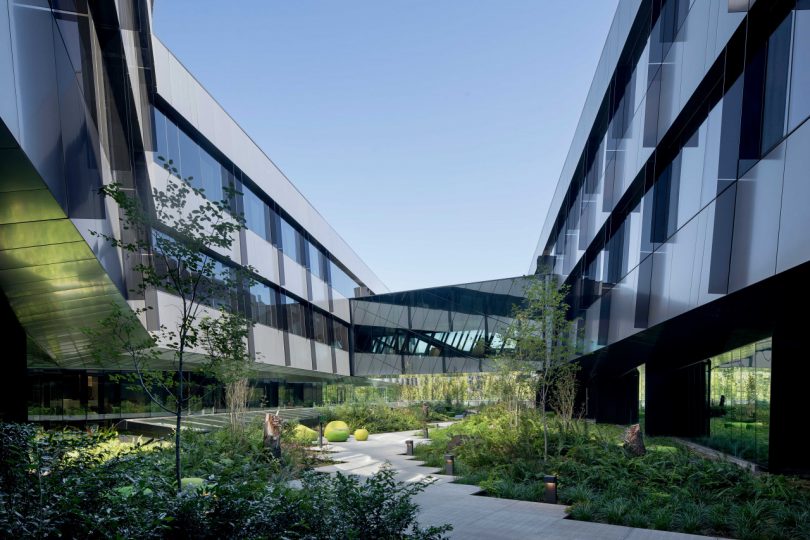 outdoor courtyard with green plants and walkway between two buildings at Serena Williams campus at Nike