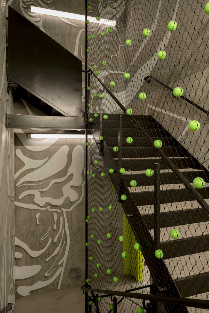 interior view of office staircase with tennis netting hanging holding tennis balls