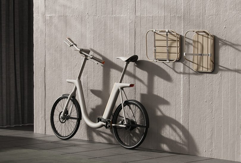 Pendler ebike leaning up against a concrete wall with front and rear baskets hanging to the right.