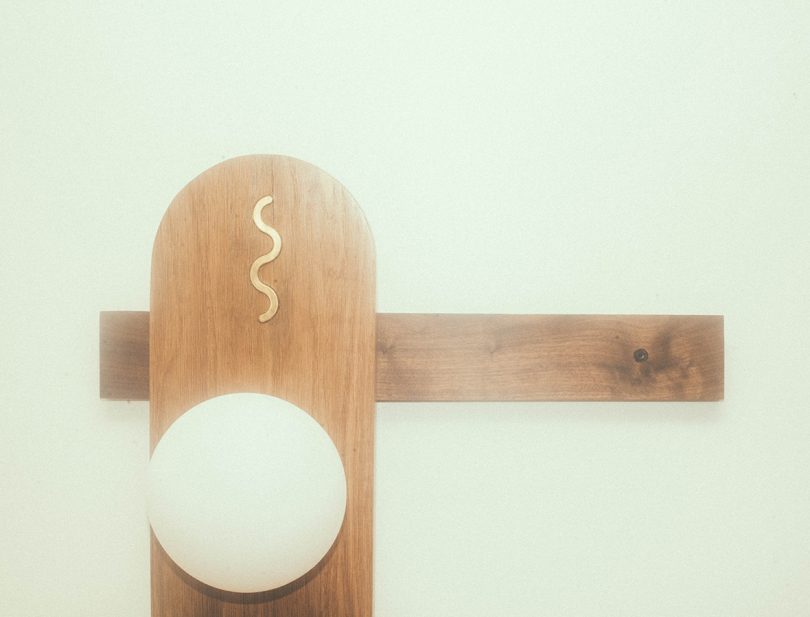 detail of abstract lamp with wood hanging on a white wall 